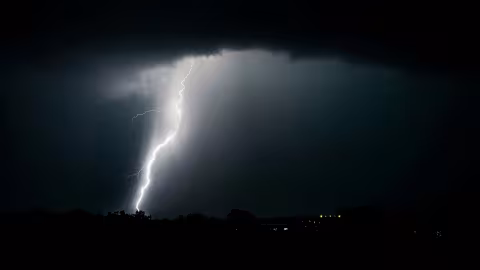 Lightning bolt striking down through a dark stormy sky.